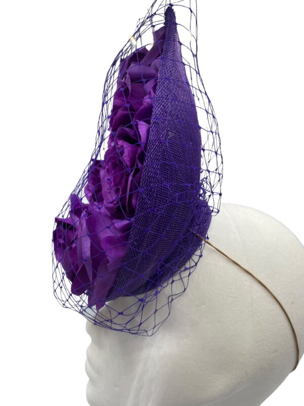 Cadbury purple coloured percher hat with purple roses in the centre and finished with a purple netting over the headpiece.